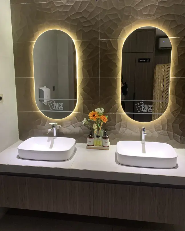 Restroom with backlit oval mirrors